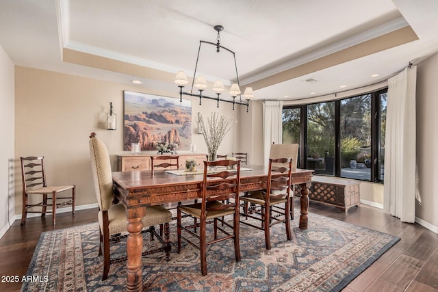 dining space featuring dark hardwood / wood-style floors, ornamental molding, and a tray ceiling