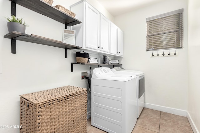 laundry area with light tile patterned flooring, cabinets, and washer and clothes dryer