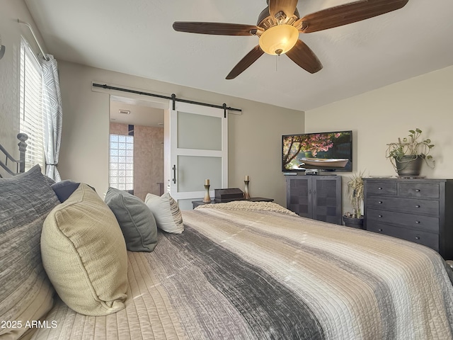 bedroom featuring multiple windows, ceiling fan, and a barn door