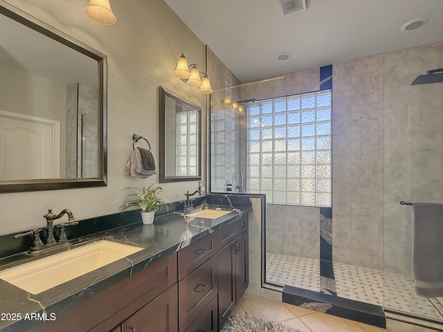 bathroom featuring vanity, a tile shower, and tile patterned flooring