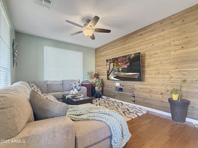 living room with wood walls, hardwood / wood-style flooring, and ceiling fan