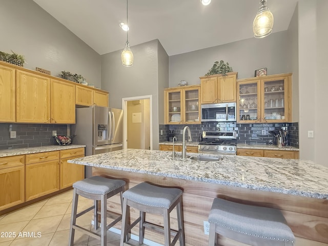 kitchen featuring a kitchen bar, appliances with stainless steel finishes, sink, decorative light fixtures, and high vaulted ceiling