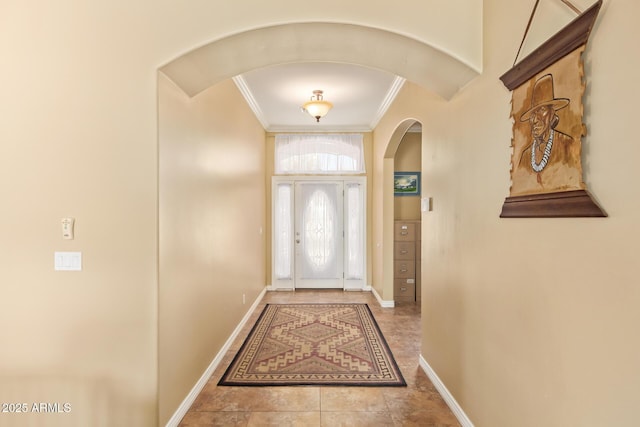 doorway to outside with ornamental molding, arched walkways, baseboards, and tile patterned floors