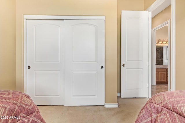 bedroom with light carpet, a closet, and baseboards