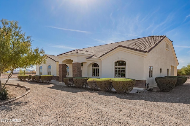 view of front of house with stone siding, a tiled roof, and stucco siding