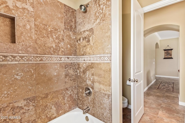 bathroom with ornamental molding, bathing tub / shower combination, toilet, and baseboards