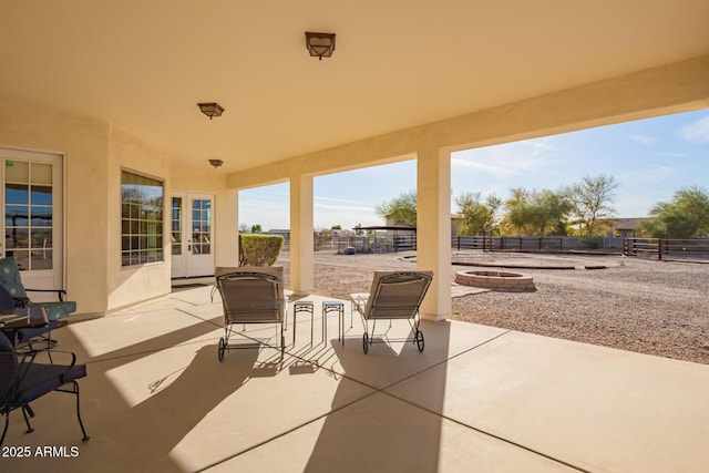 view of patio / terrace featuring a fire pit, french doors, and fence