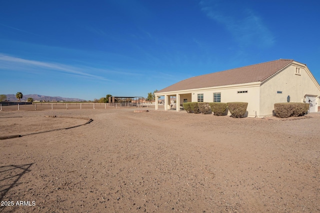 exterior space with a mountain view, fence, and stucco siding