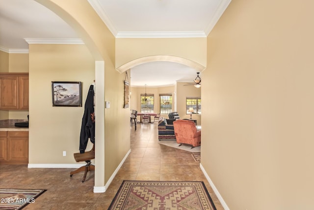 hall with ornamental molding, arched walkways, tile patterned flooring, and baseboards