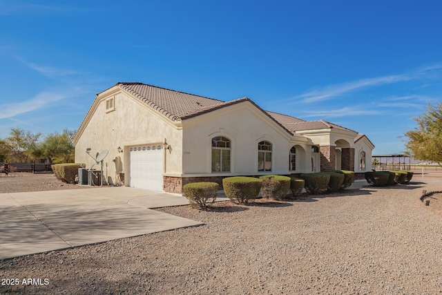 view of front of home featuring an attached garage, driveway, stone siding, a tiled roof, and stucco siding