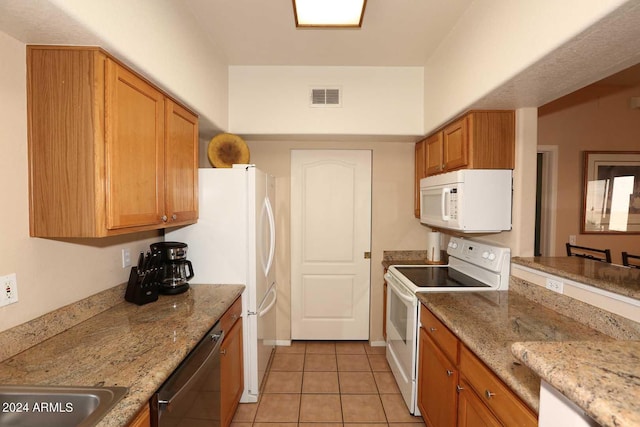 kitchen featuring light tile floors, white appliances, and light stone counters