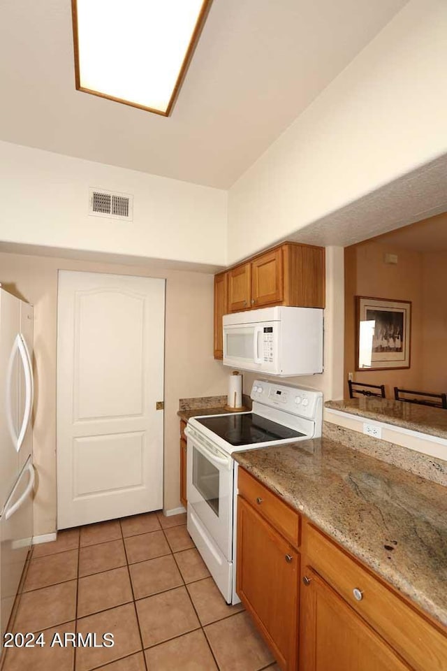 kitchen with white appliances, light stone counters, and light tile floors