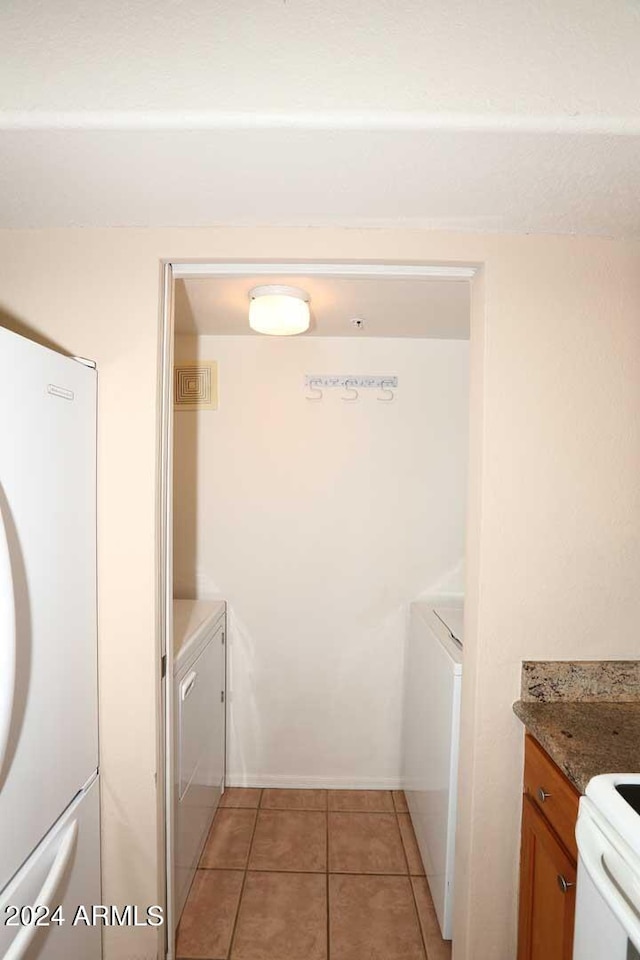 clothes washing area featuring washer and clothes dryer and light tile flooring