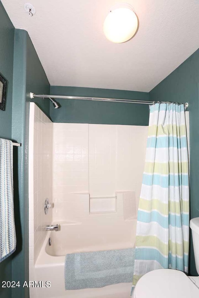 bathroom with shower / bath combination with curtain and toilet