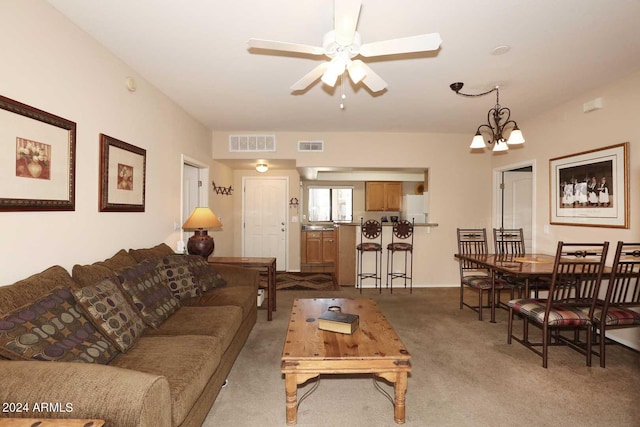 carpeted living room featuring ceiling fan with notable chandelier