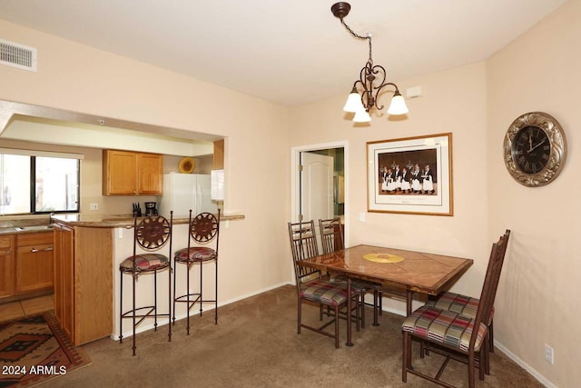 carpeted dining space featuring an inviting chandelier