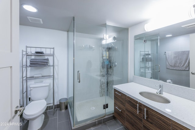 bathroom featuring vanity, a shower with shower door, tile patterned floors, and toilet