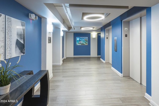 corridor featuring elevator and light hardwood / wood-style flooring