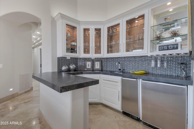 kitchen with tasteful backsplash, kitchen peninsula, white cabinets, and refrigerator