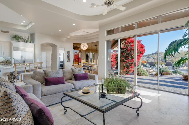 living room featuring a towering ceiling, ceiling fan, and a tray ceiling