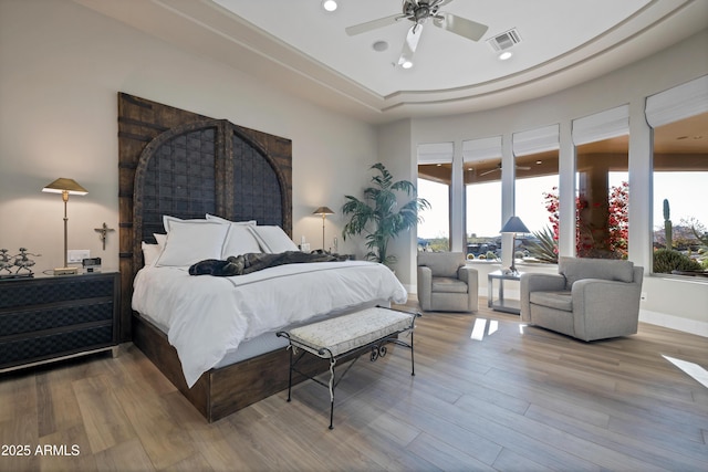 bedroom featuring ceiling fan, a tray ceiling, and hardwood / wood-style floors