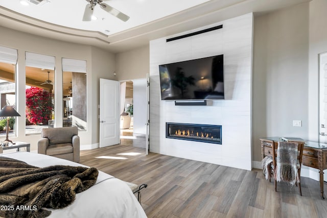 bedroom featuring hardwood / wood-style flooring, a fireplace, and a raised ceiling