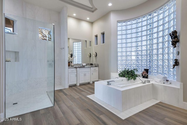 bathroom featuring hardwood / wood-style flooring, vanity, and plus walk in shower