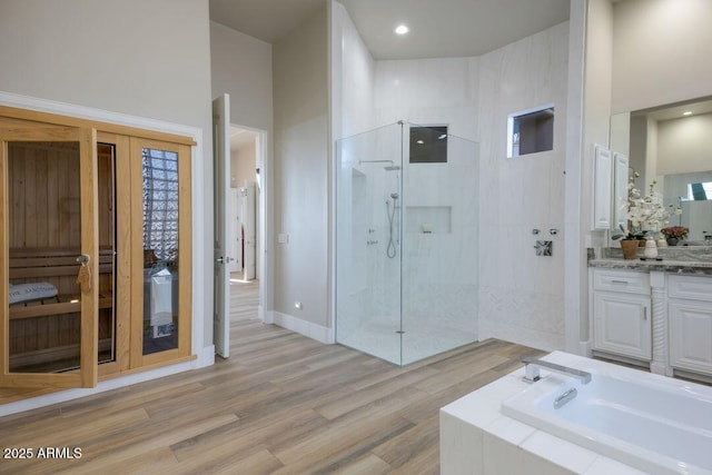 bathroom featuring wood-type flooring, shower with separate bathtub, and vanity