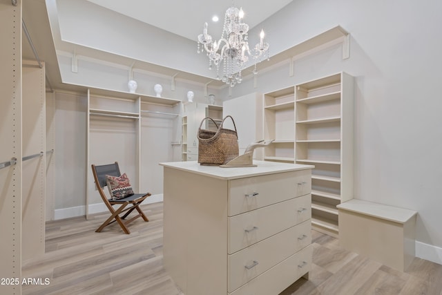 spacious closet featuring an inviting chandelier and light hardwood / wood-style floors