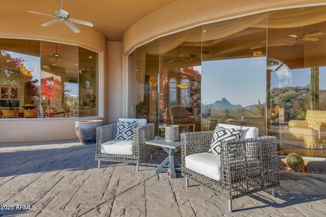 view of patio with ceiling fan, an outdoor living space, and a mountain view