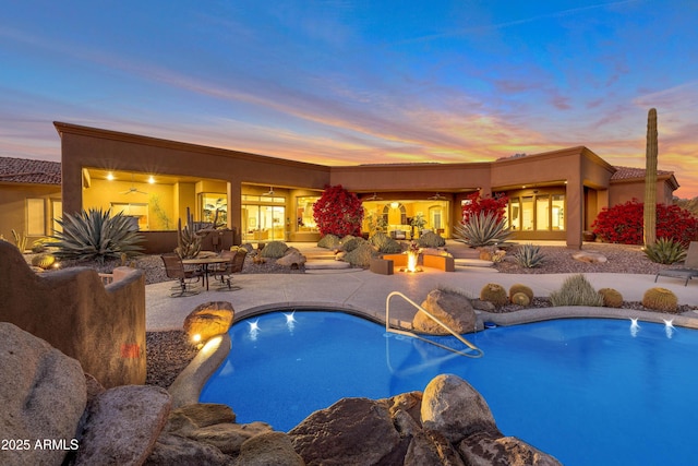 pool at dusk with a patio area