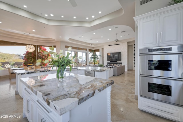 kitchen featuring light stone counters, ceiling fan, stainless steel appliances, and a spacious island