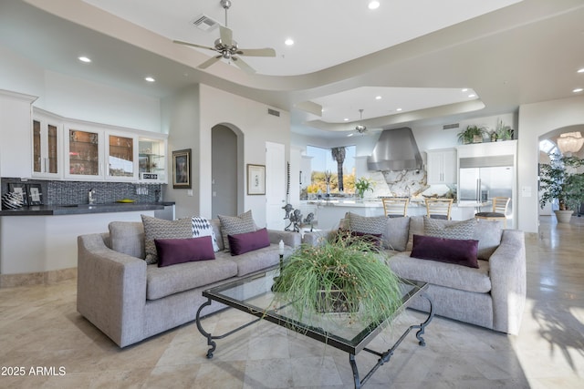 living room with a tray ceiling and ceiling fan