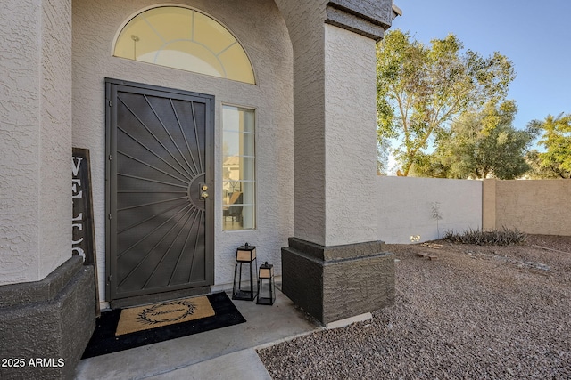 doorway to property with fence and stucco siding