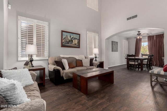 6862 W Honeysuckle Dr, Peoria, AZ 85383 - living area featuring arched walkways, ceiling fan, dark wood-type flooring, a high ceiling, and baseboards