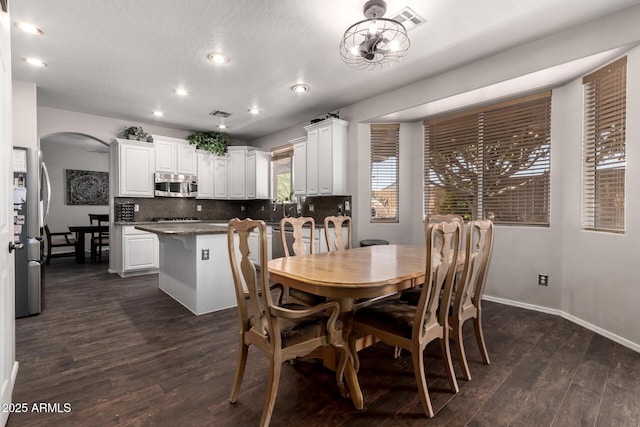6862 W Honeysuckle Dr, Peoria, AZ 85383 - dining area featuring arched walkways, dark wood-type flooring, recessed lighting, and baseboards