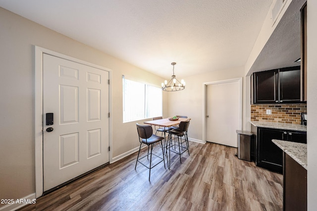 dining area featuring light hardwood / wood-style flooring, a chandelier, and a textured ceiling