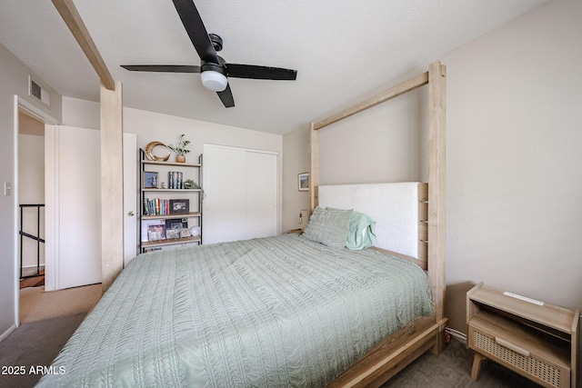 carpeted bedroom with a textured ceiling, ceiling fan, and a closet