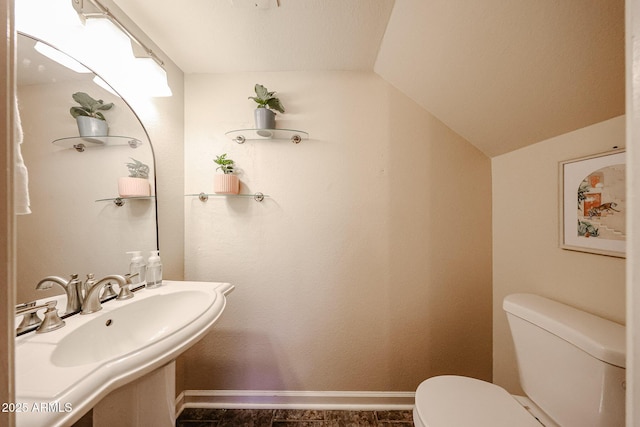 bathroom with vaulted ceiling, sink, and toilet