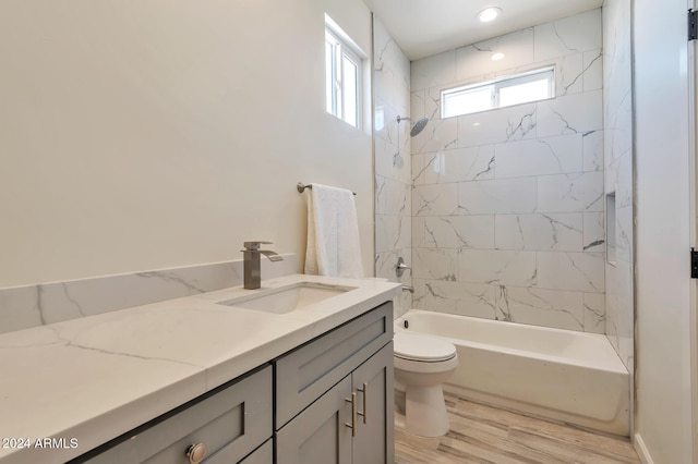 full bathroom with vanity, toilet, wood-type flooring, and tiled shower / bath