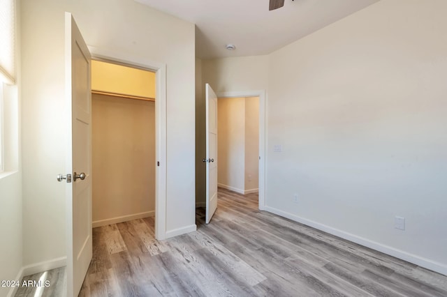 unfurnished bedroom with a walk in closet, a closet, and light wood-type flooring