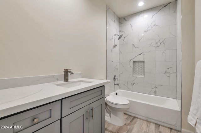 full bathroom featuring hardwood / wood-style flooring, vanity, toilet, and tiled shower / bath