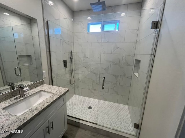 bathroom featuring a shower with door and vanity