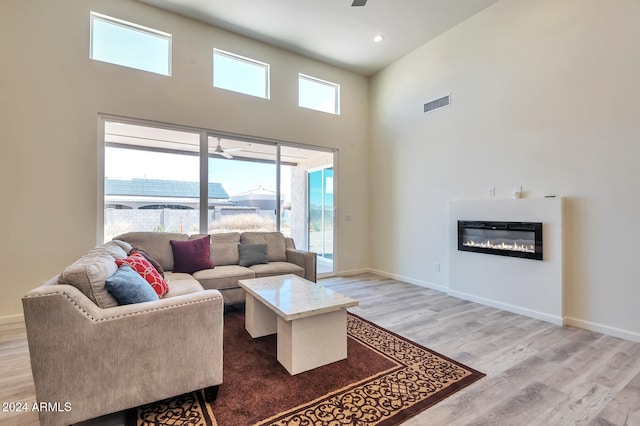 living room with ceiling fan, wood-type flooring, a high ceiling, and a wealth of natural light