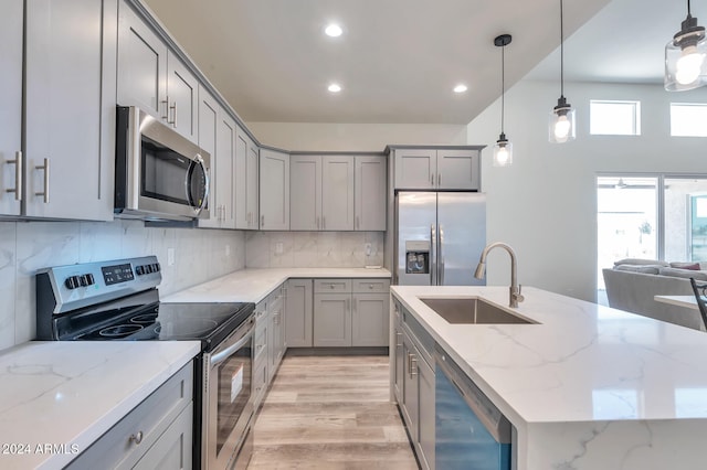 kitchen featuring light stone countertops, appliances with stainless steel finishes, pendant lighting, and sink