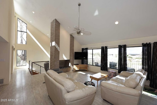 living area with high vaulted ceiling, plenty of natural light, visible vents, and a ceiling fan