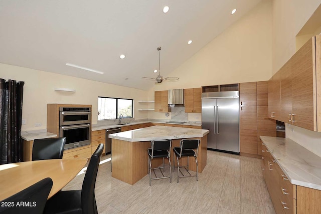 kitchen featuring brown cabinetry, a kitchen breakfast bar, a center island, stainless steel appliances, and a sink