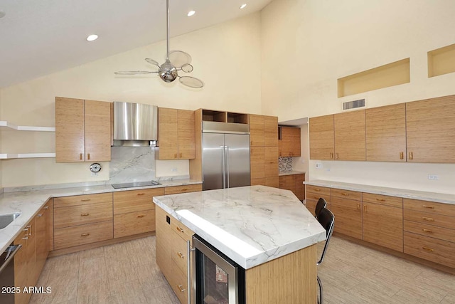 kitchen featuring beverage cooler, appliances with stainless steel finishes, light stone countertops, wall chimney range hood, and open shelves