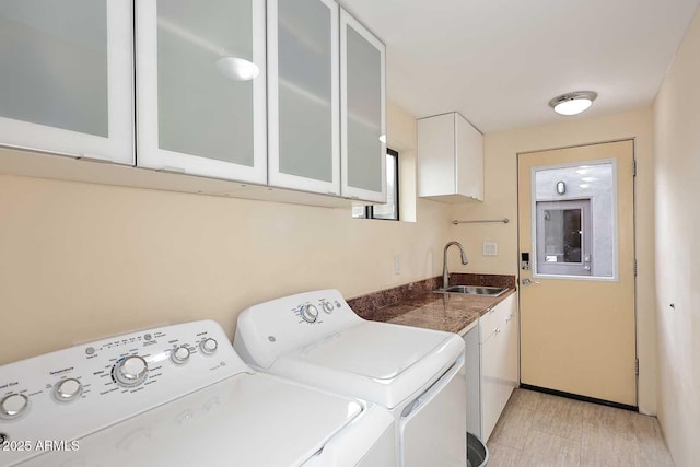 washroom with washing machine and dryer, cabinet space, and a sink