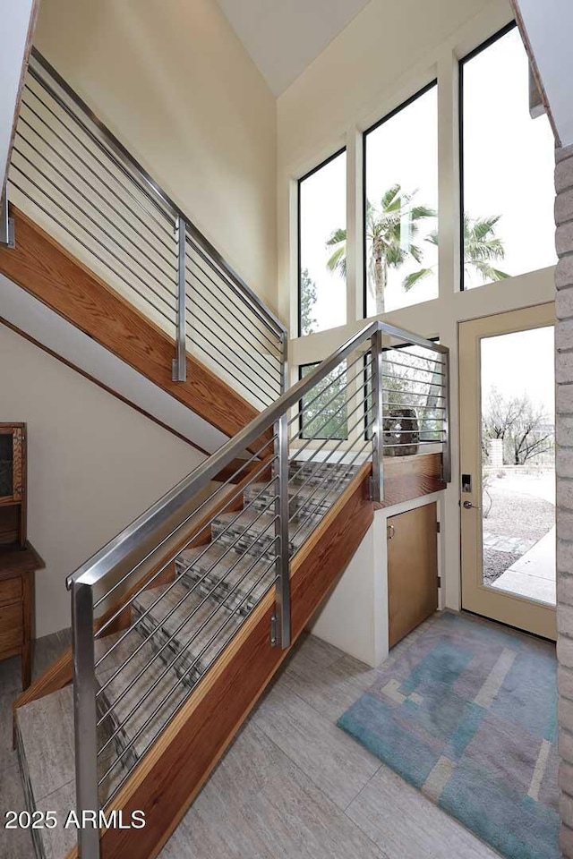 stairway with a high ceiling and wood finished floors